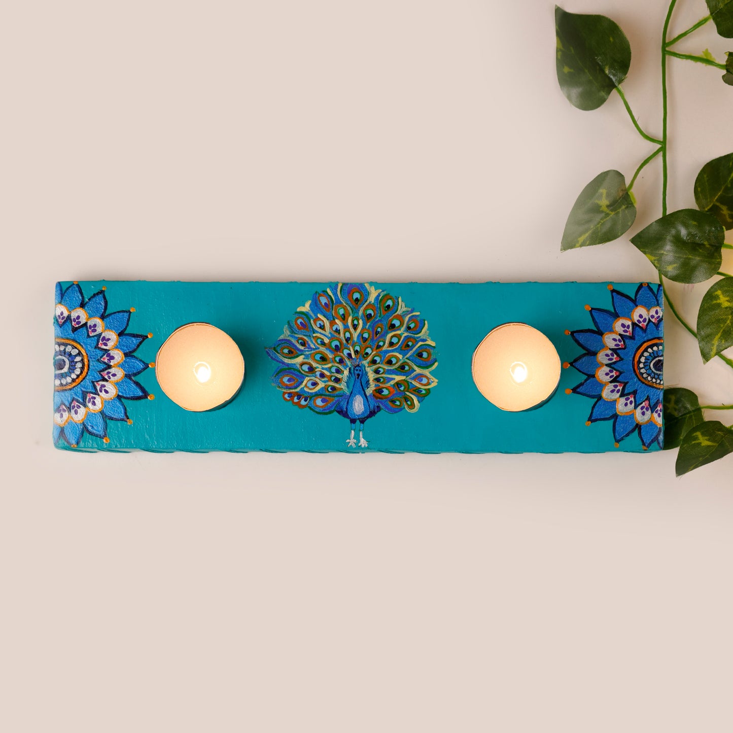 GlowingPlumes-Tea-Light-Holder-showcasing-intricate-peacock-design-in-blue-on-wooden-surface.jpg